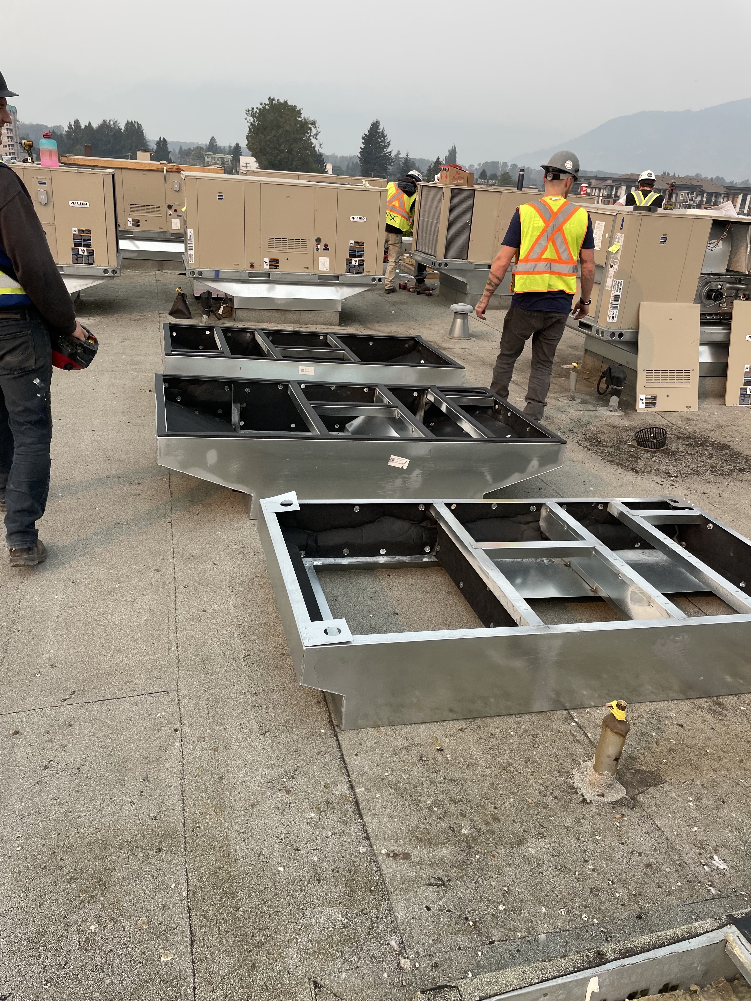 Alpine Refrigeration technicians installing commercial rooftop HVAC curb adapters and make-up air system components in Fraser Valley