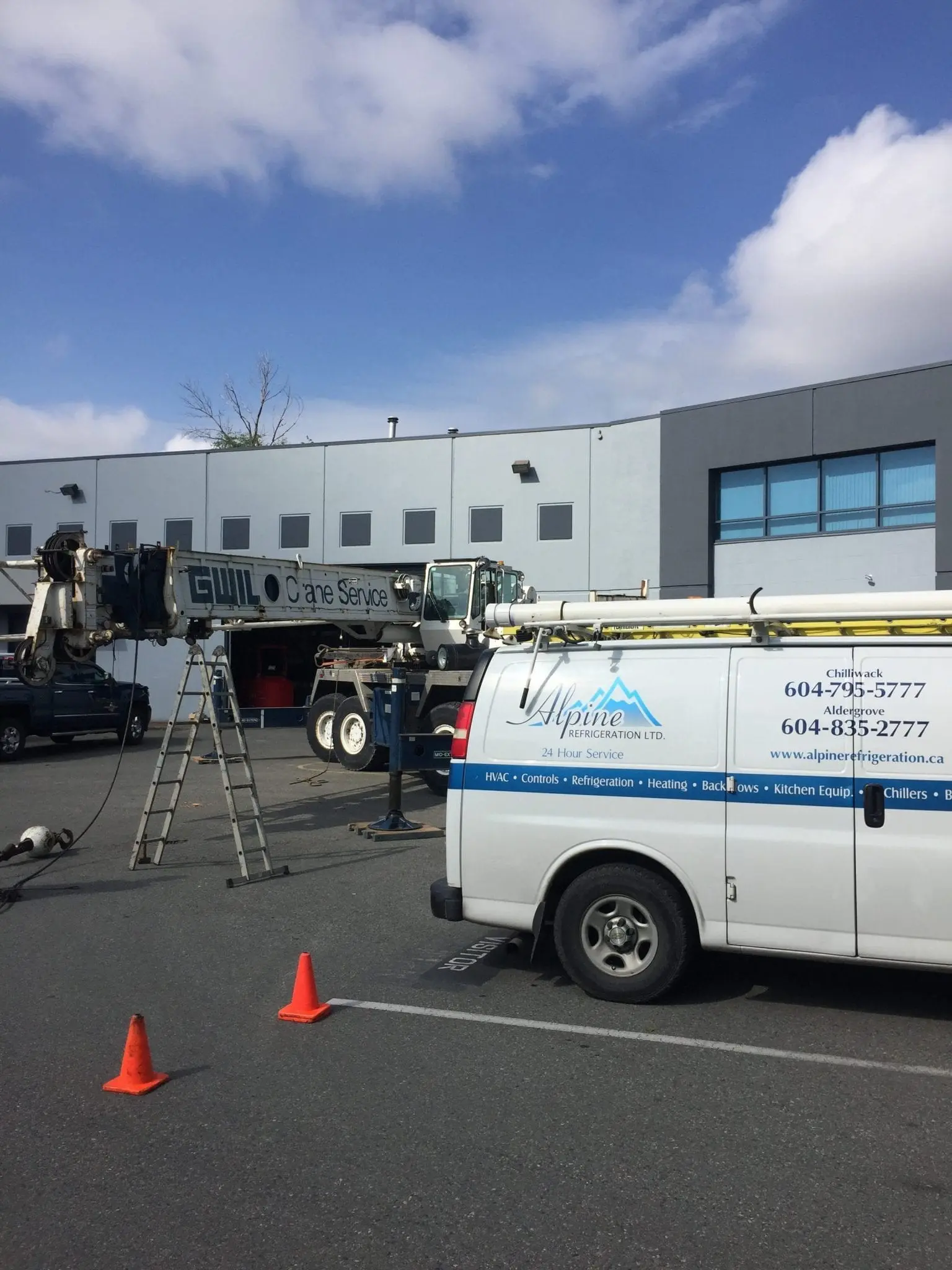 Alpine Refrigeration van with crane service at commercial HVAC installation site