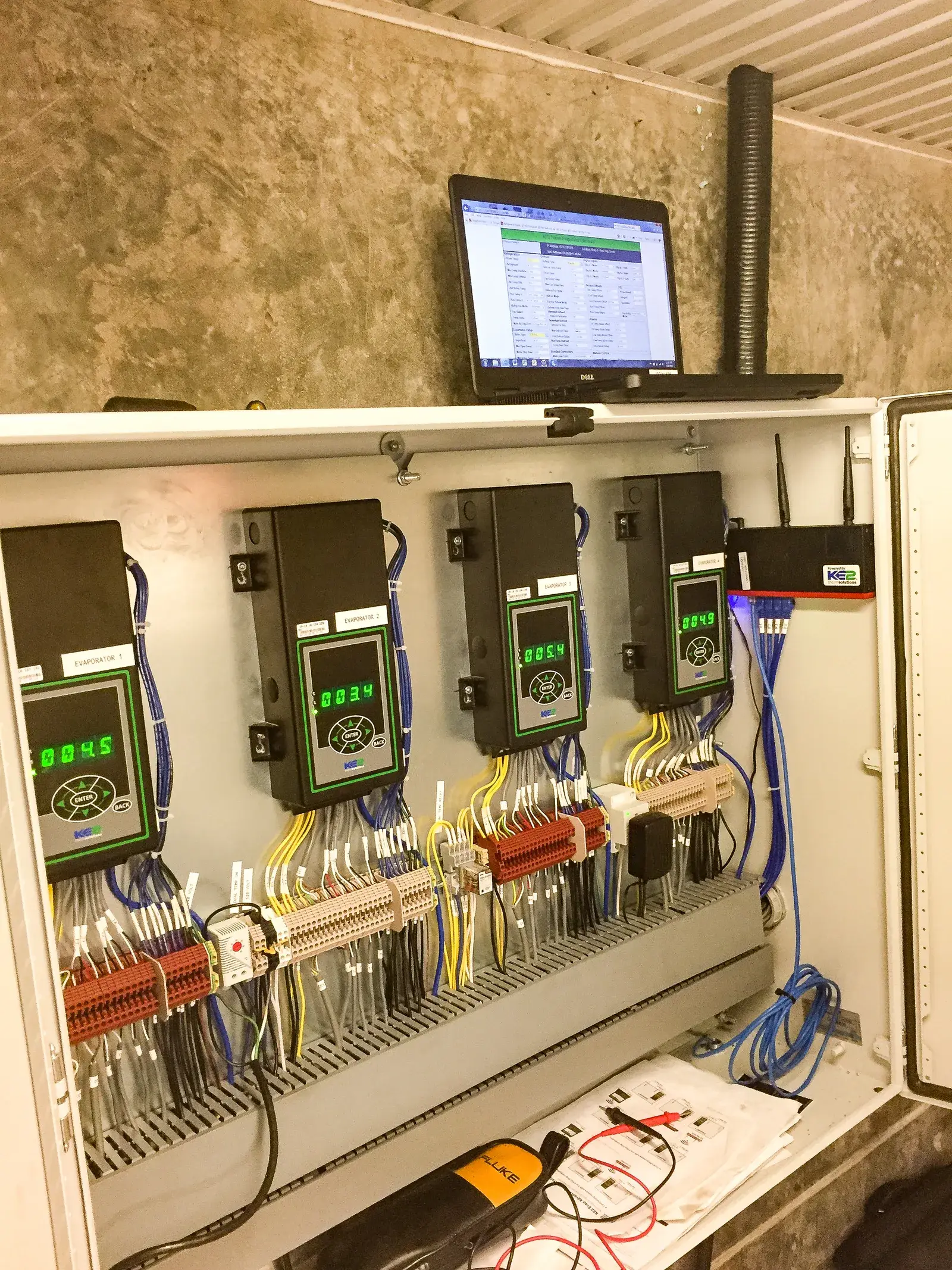 Alpine technician commissioning a multi-evaporator KE2 refrigeration control panel with laptop diagnostics