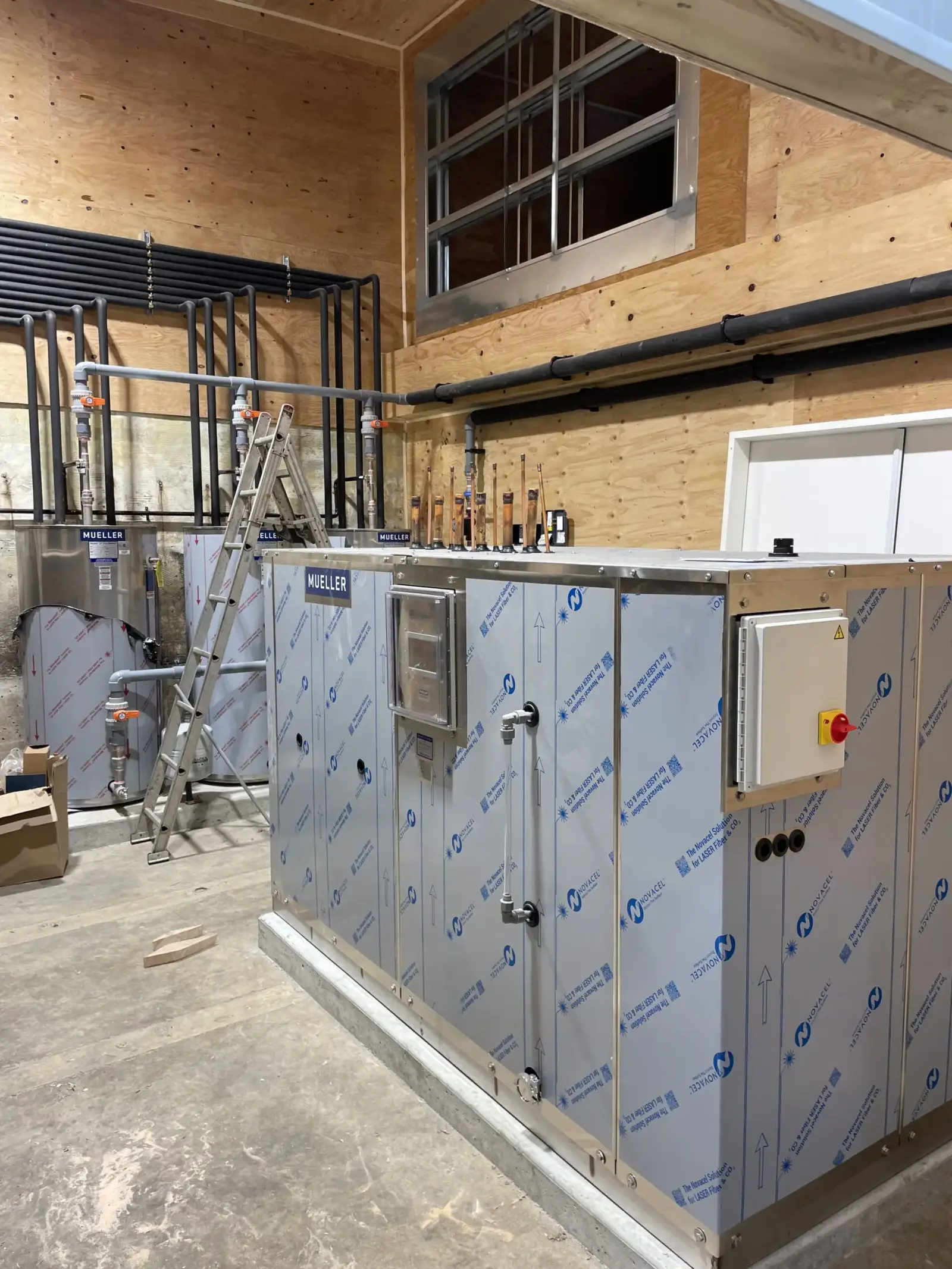 Custom heating system installation with Mueller tanks and Novacel-wrapped air handler in mechanical room