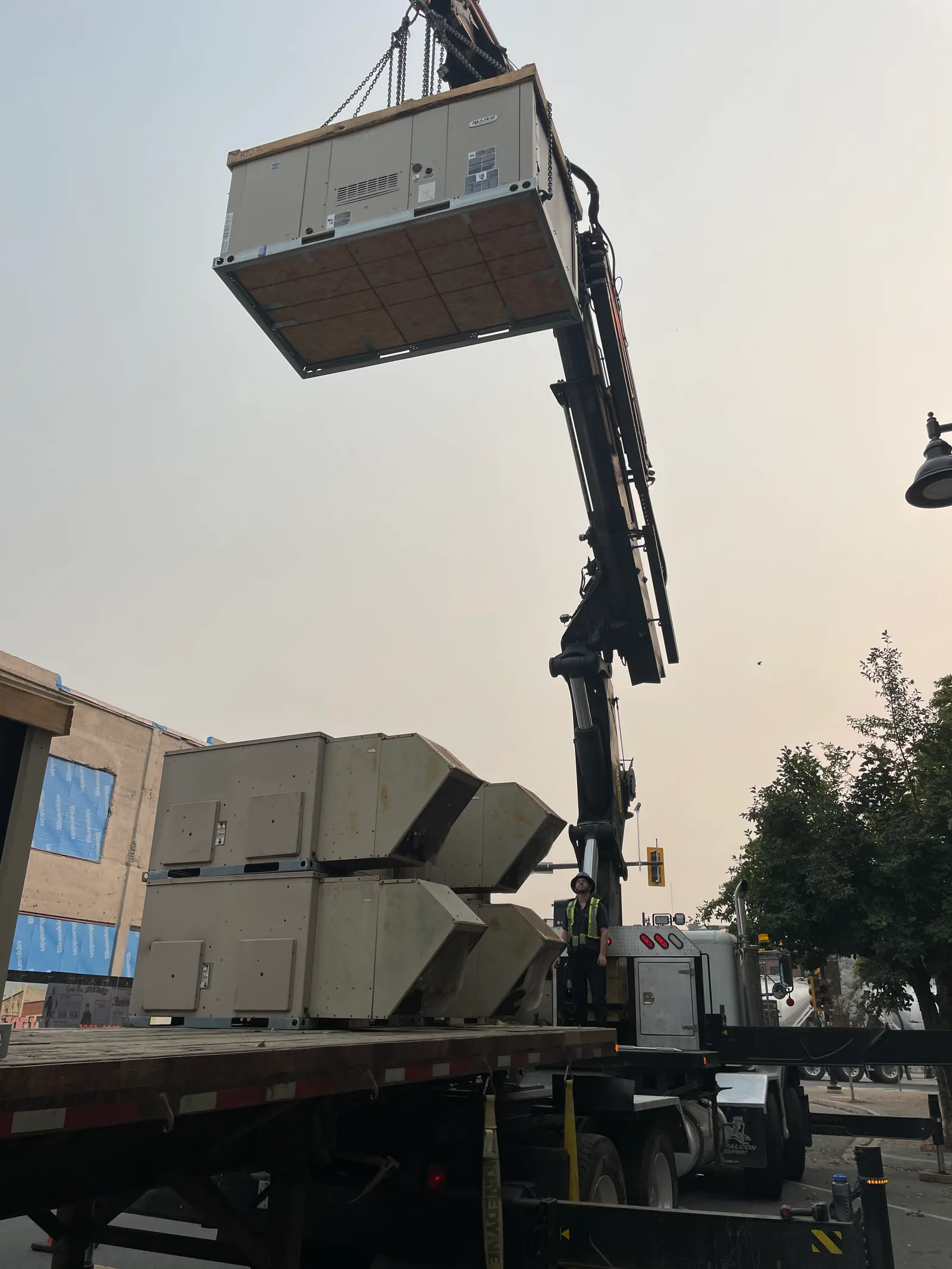 Crane hoisting commercial make-up air units onto a Fraser Valley rooftop install