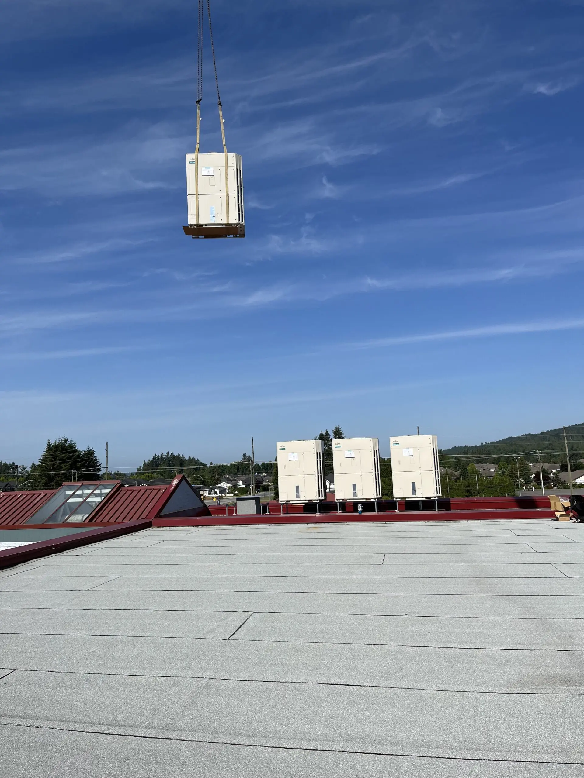 Crane lifting Fujitsu heat pump units onto Mission school rooftop for hybrid heat pump retrofit at Christine Morrison Elementary BC